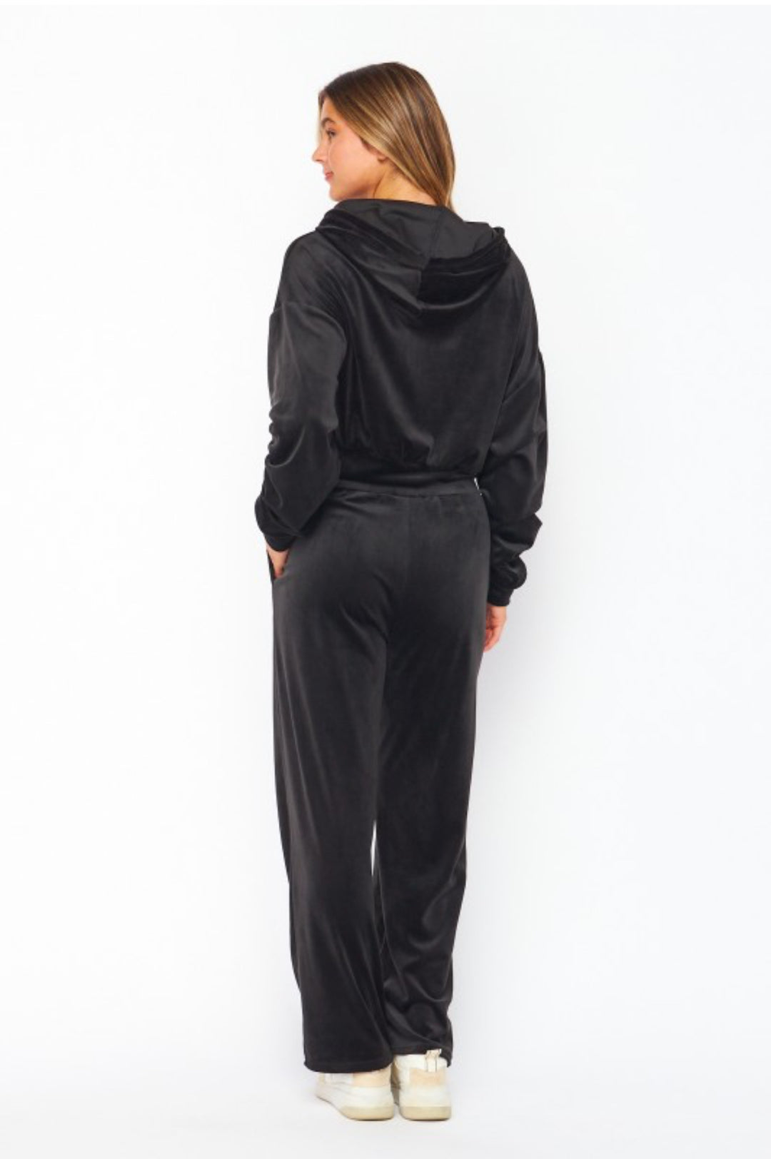 Person wearing a black hoodie and pants set on a white background