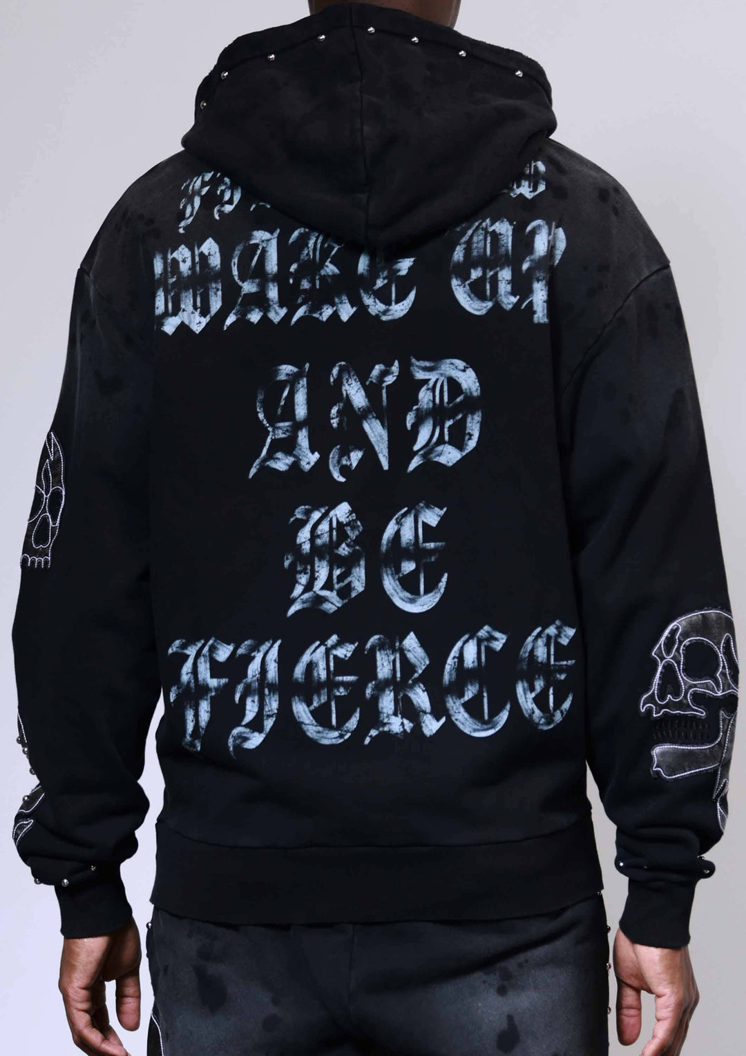 Black hoodie with white text on the back, worn by a person against a light gray background