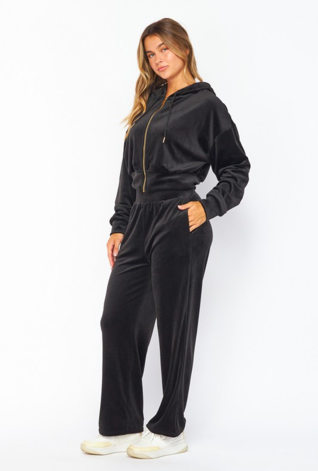 Woman wearing a black velour tracksuit on a white background