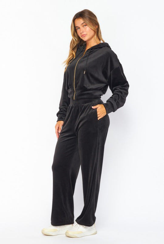 Woman wearing a black velour tracksuit on a white background
