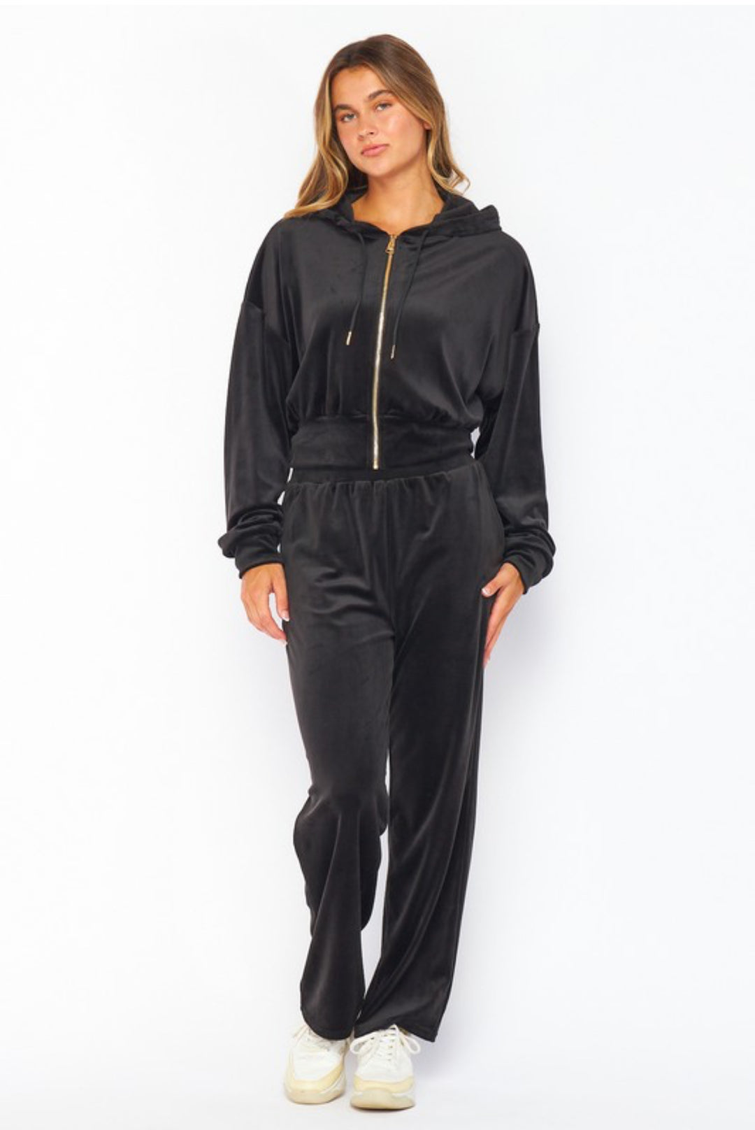 Woman wearing a black velour tracksuit on a white background