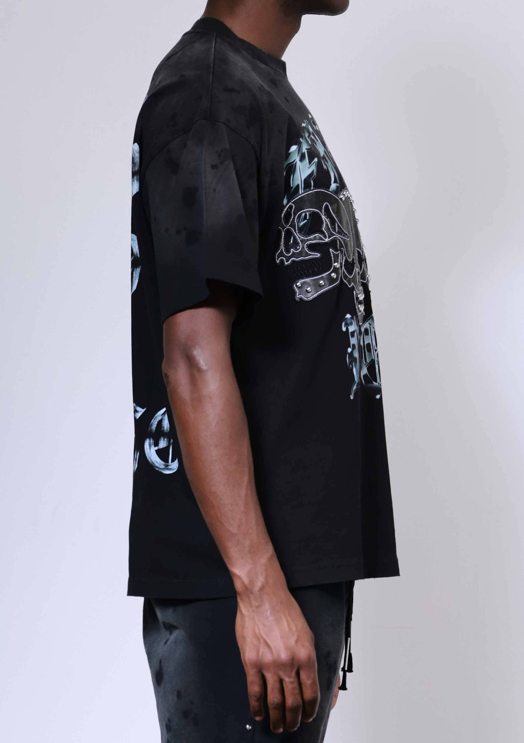 Person wearing a black t-shirt with graphic designs on a plain background