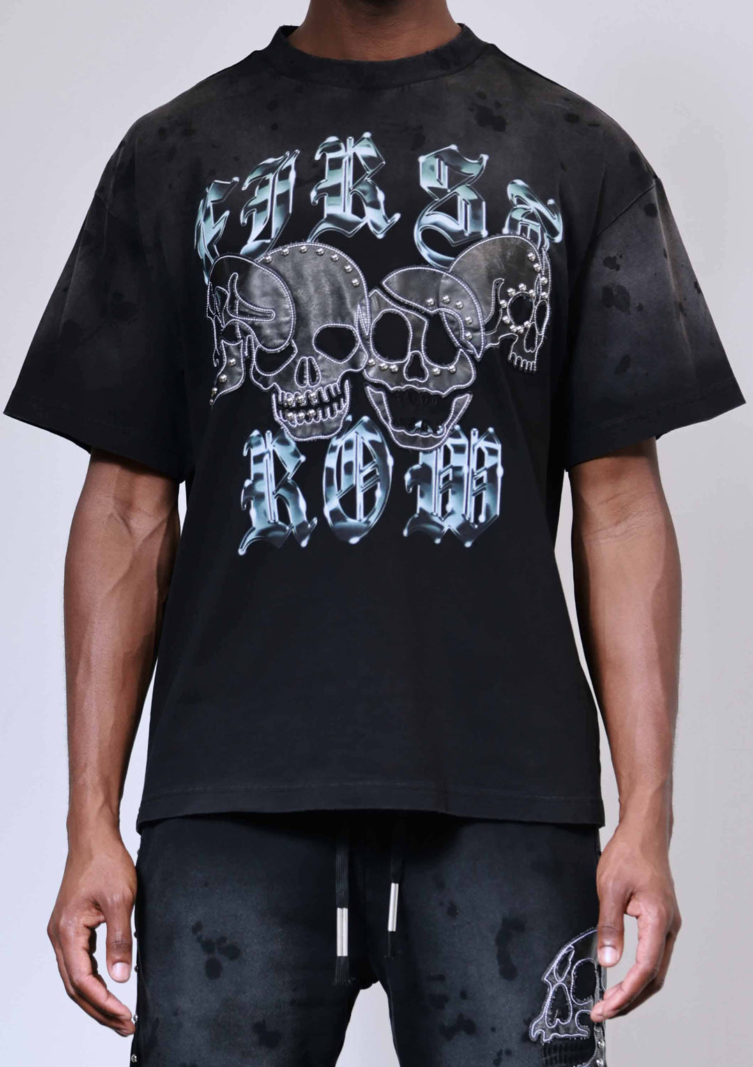 Black t-shirt with skull design and text worn by a person on a white background